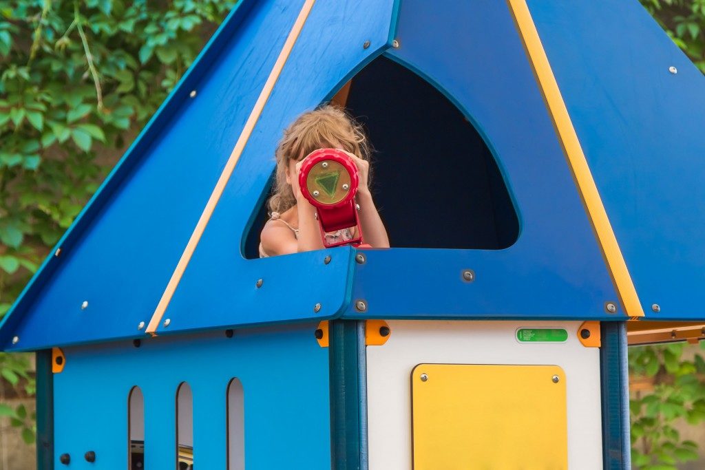 girl in the children's house, looking into the children's telescope, playground