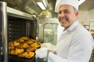 baker putting bread in the oven
