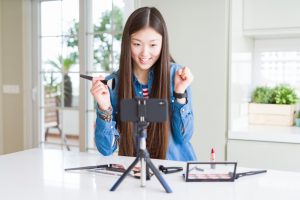 a girl holding makeup products and broadcasting using her mobile phone