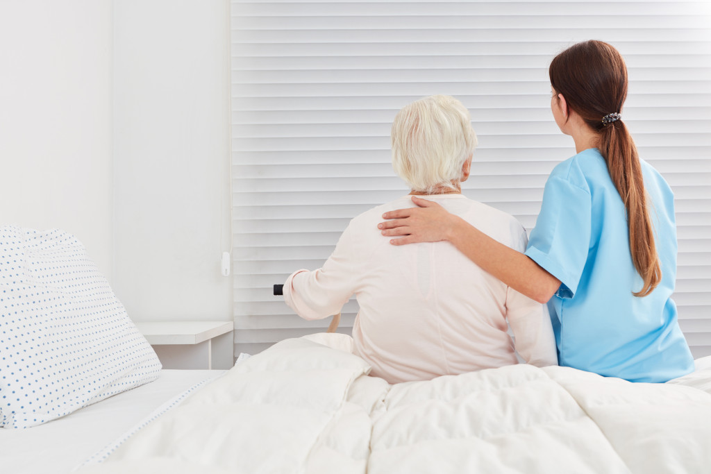 caregiver assisting senior from getting up from the bed