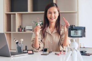 a young woman holding makeup products in front of a camer