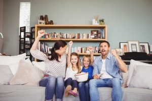 a family of four watching a movie on a sofa