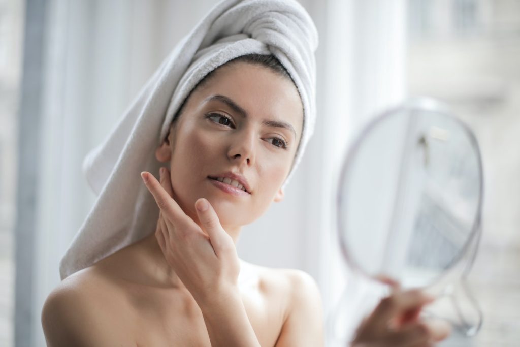 elective Focus Portrait Photo of Woman With a Towel on Head Looking in the Mirror