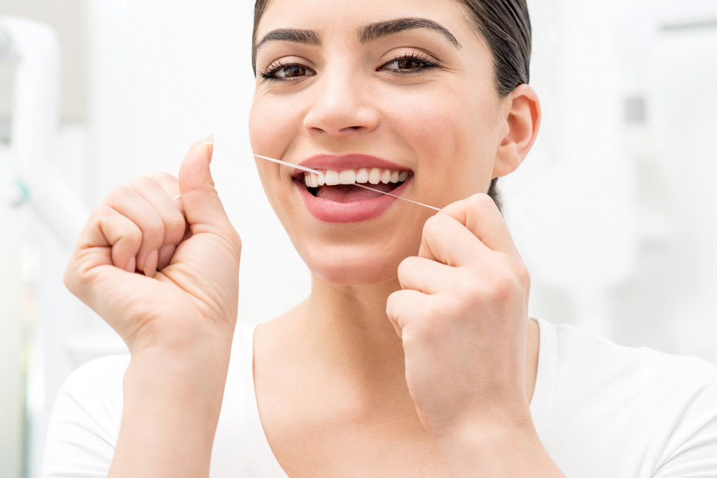 young woman flossing concept of oral hygiene
