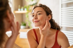 curly haired woman checking her face in the mirror