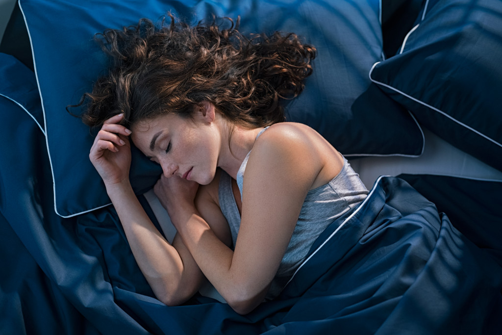 young woman sleeping on her side in blue sheets