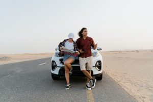 Man and Woman Holding a Map While Standing In Front of the White car