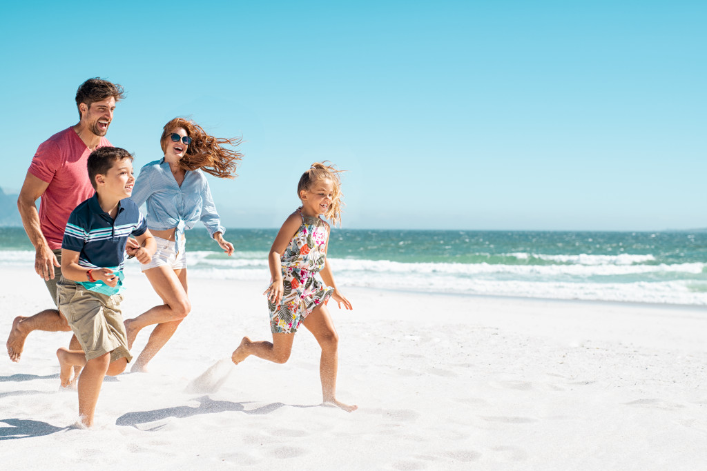 Small family running on the sand in a beach.