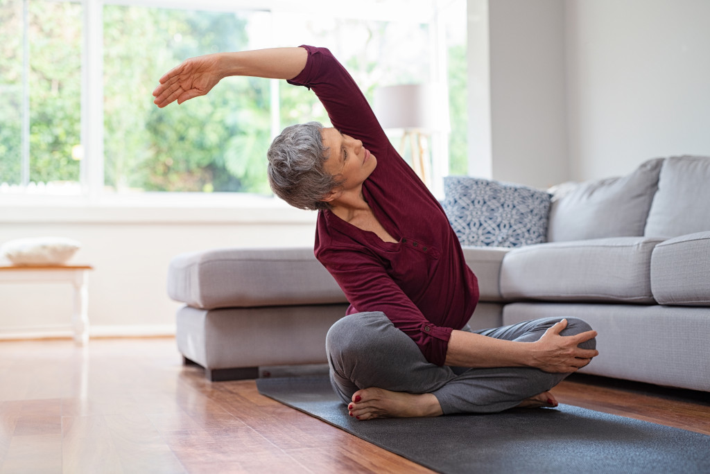 an elderly woman practicing yoga at home