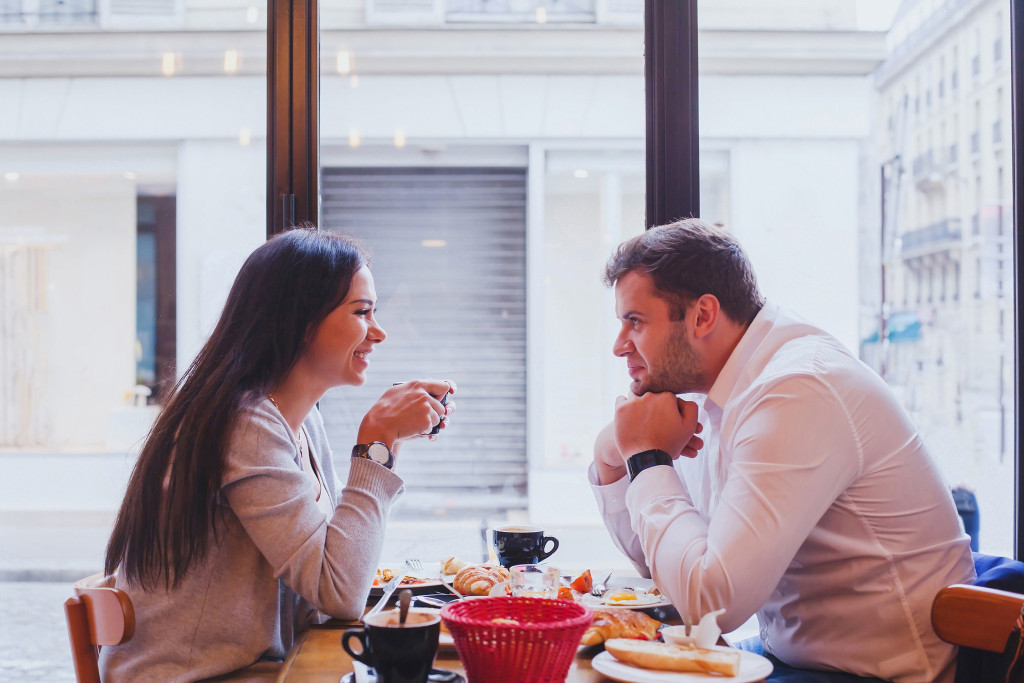 A man and a woman talking and listening to each other while eating at a cafe