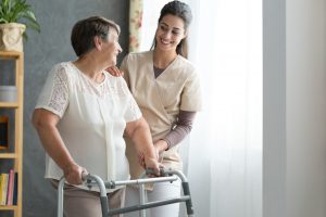 nurse helping senior walk at home